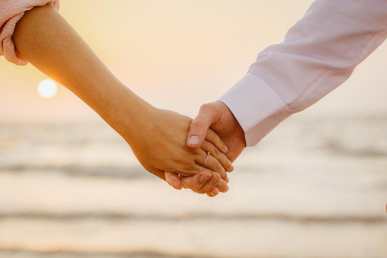 Married couple holding hands at sunrise at the beach
