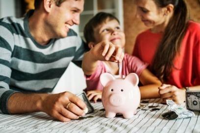 couple with child putting money in a piggy bank