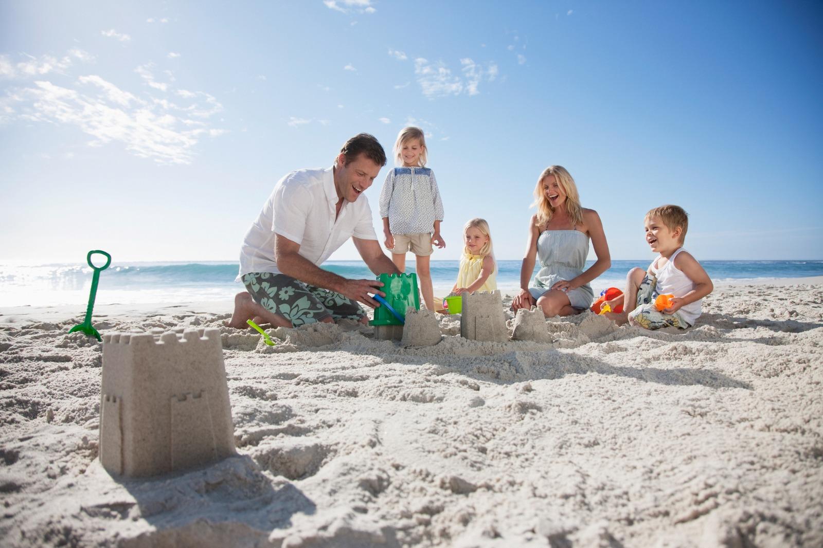Family building sandcastles on the beach with Dad