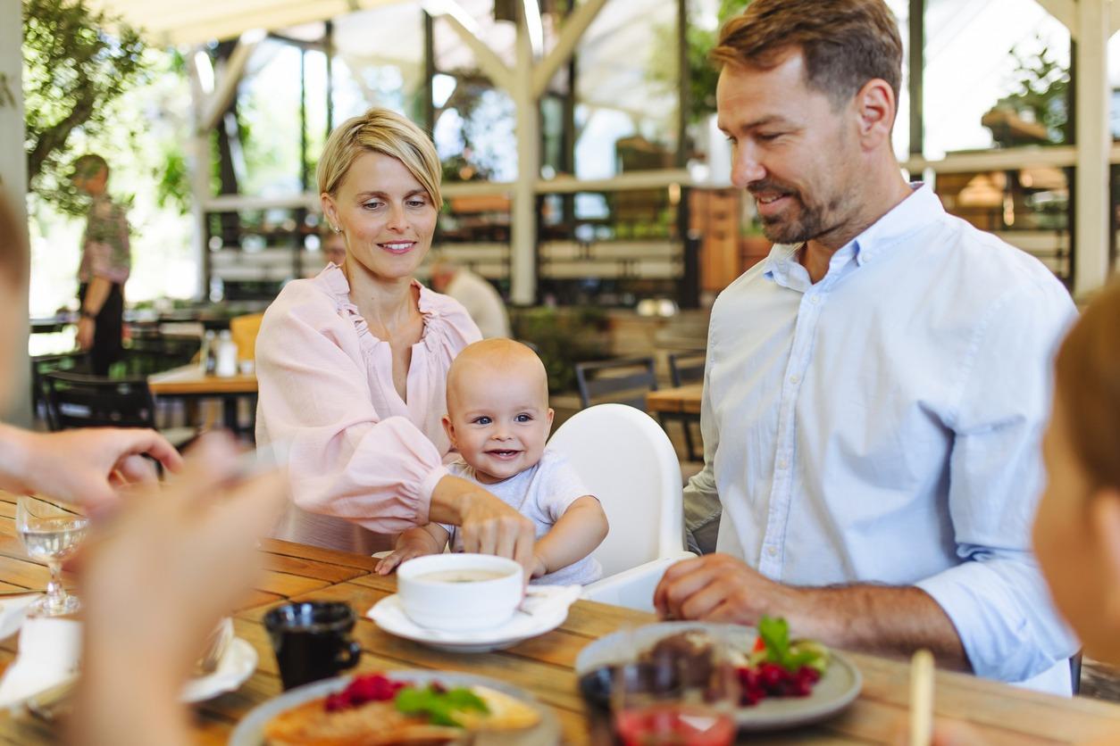 family enjoying dinner at a local restaurant with their child who is sitting in a high chair.