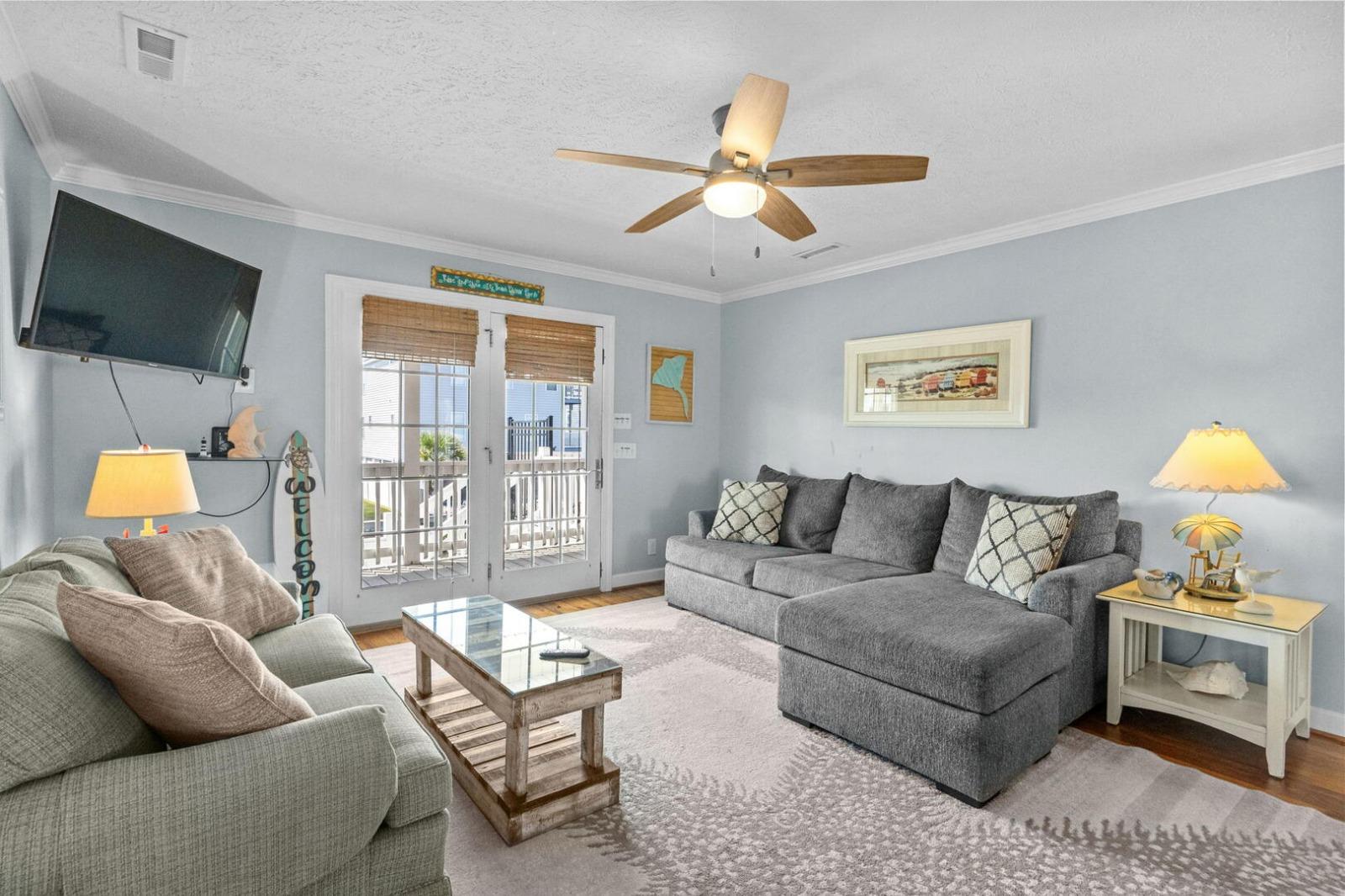 Spacious living room with sectional sofa and balcony access in a North Myrtle Beach condo rental managed by Seaside Vacations.