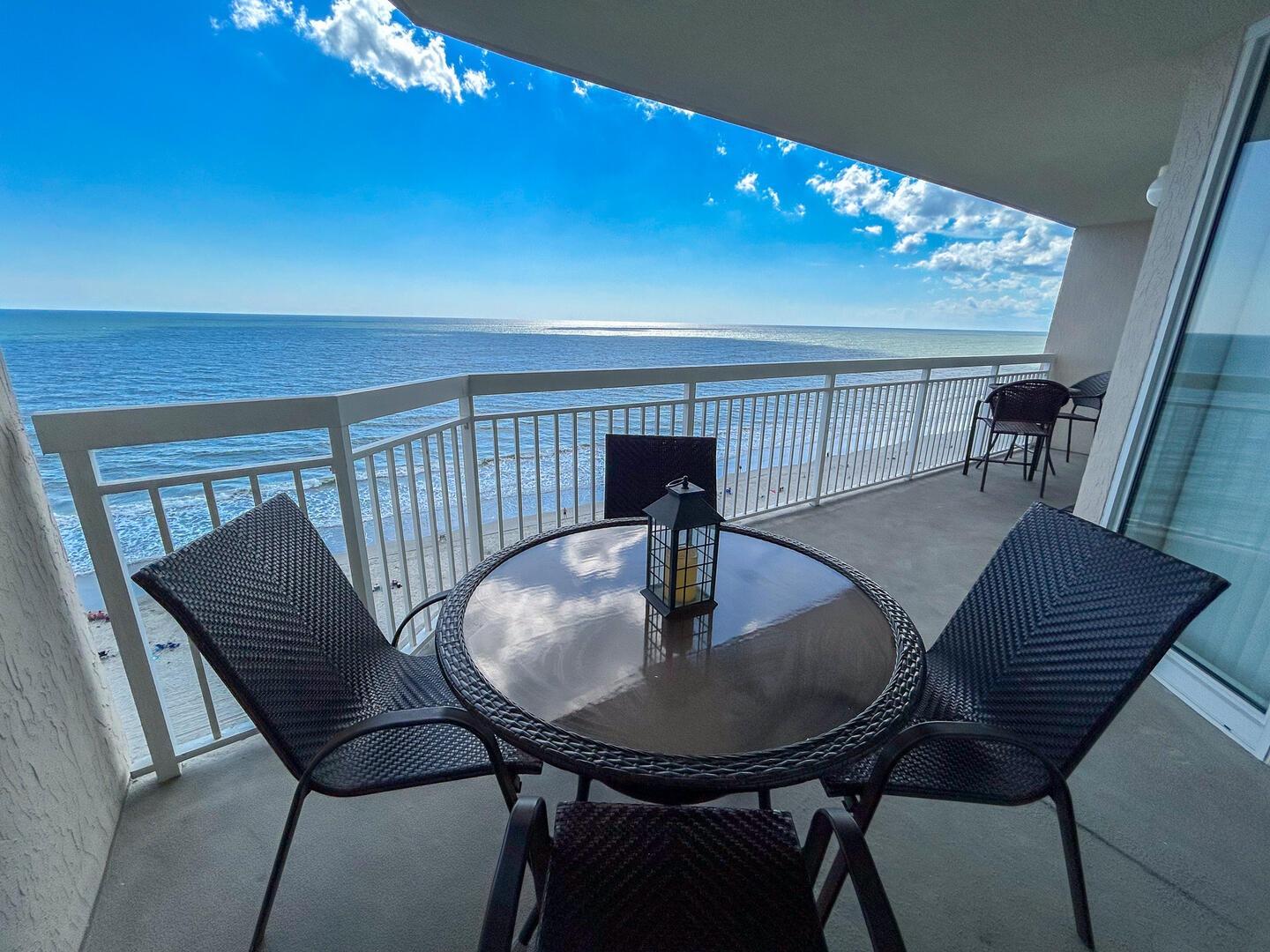 Private balcony of a North Myrtle Beach oceanfront condo featuring outdoor dining furniture and a high-rise view of the Atlantic Ocean