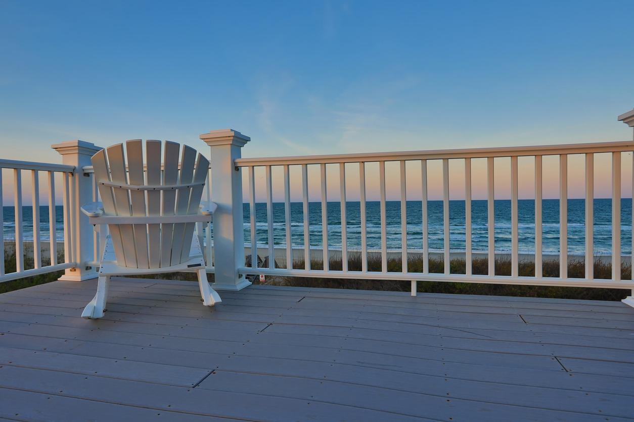 Empty Adirondack chair on a balcony deck overlooking the beach and the ocean in North Myrtle Beach.
