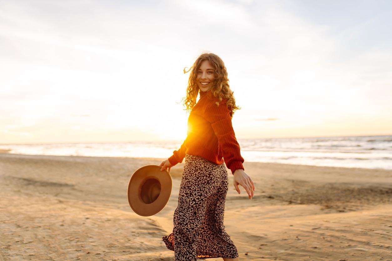 Portrait of a beautiful woman walking alone on empty seashore in cold weather.